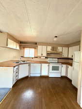 Kitchen featuring white cabinets, a sink, dark wood-type flooring, and white appliances
