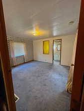 Carpeted spare room featuring baseboards, visible vents, wallpapered walls, and a textured ceiling