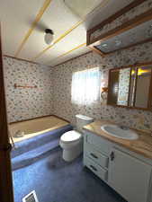 Full bathroom featuring vanity, a textured ceiling, wallpapered walls, visible vents, and a bath