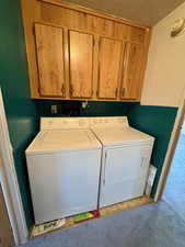 Laundry area featuring independent washer and dryer, cabinet space, and light colored carpet
