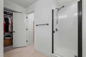 Full bath featuring a stall shower, tile patterned floors, and a spacious closet