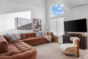Living room with a high ceiling and light carpet