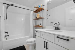Full bath featuring tile patterned flooring, vanity, toilet, visible vents, and shower / bath combination with curtain