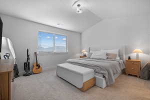 Bedroom with baseboards, visible vents, vaulted ceiling, and light colored carpet