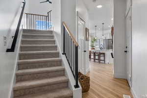 Stairway featuring baseboards, visible vents, wood finished floors, and recessed lighting