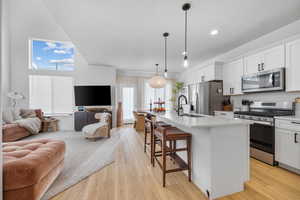 Kitchen featuring white cabinetry, stainless steel appliances, light wood-style floors, and open floor plan