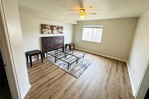 Bedroom featuring baseboards, a ceiling fan, wood finished floors, and a textured ceiling