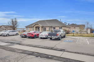 View of front of property featuring stucco siding, a shingled roof, uncovered parking, and fence