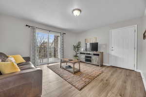 Living room with a textured ceiling, baseboards, and wood finished floors