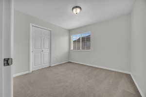 Carpeted spare room featuring baseboards and a textured ceiling