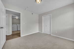 Unfurnished bedroom with carpet, baseboards, separate washer and dryer, and visible vents