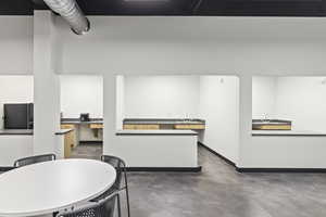 Kitchen featuring freestanding refrigerator, concrete flooring, a sink, and baseboards