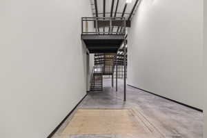 Stairs with baseboards, a high ceiling, and concrete flooring