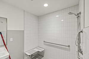 Bathroom featuring tile walls, tiled shower, and a sink