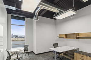 Home office with baseboards and dark colored carpet