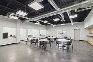 Dining area featuring finished concrete flooring, baseboards, and a towering ceiling