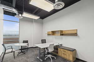 Home office with baseboards and dark colored carpet
