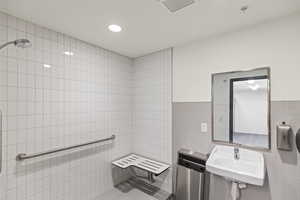 Bathroom featuring a sink, visible vents, a tile shower, and tile walls