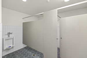 Bathroom with wainscoting, tile walls, and walk in shower