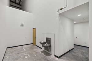 Interior space featuring a high ceiling, concrete flooring, baseboards, and recessed lighting