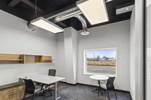 Office space with baseboards and dark colored carpet