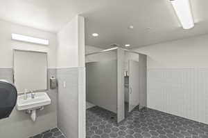Full bathroom with tile walls, recessed lighting, a wainscoted wall, a sink, and a walk in shower