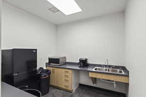 Office area with finished concrete flooring, a sink, and visible vents