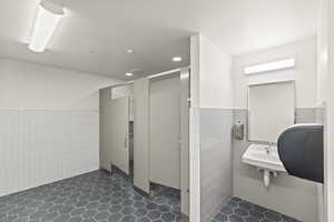 Bathroom with wainscoting, recessed lighting, and tile walls
