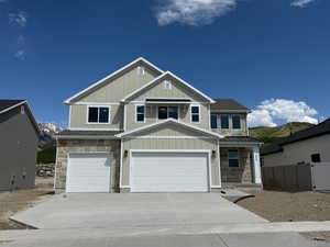 Craftsman house featuring stone siding, driveway, a mountain view, and board and batten siding