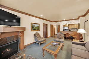 Living area featuring baseboards, ornamental molding, recessed lighting, and a tiled fireplace