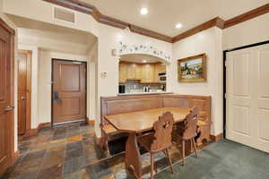 Dining area with baseboards, ornamental molding, visible vents, and stone tile floors