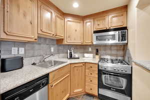 Kitchen featuring light countertops, a sink, stainless steel appliances, and light brown cabinetry