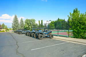 Uncovered parking lot with a tennis court and fence