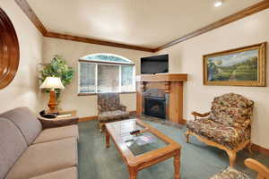 Carpeted living area with baseboards, a fireplace, and crown molding