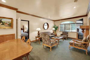 Carpeted living area featuring crown molding, a glass covered fireplace, a textured ceiling, baseboards, and recessed lighting