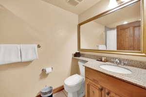 Bathroom with tile patterned floors, visible vents, toilet, and vanity