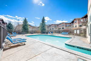 Community pool featuring fence and a patio area