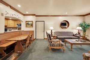 Living area featuring baseboards, ornamental molding, recessed lighting, arched walkways, and dark colored carpet
