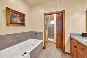 Full bath featuring vanity, tile patterned floors, a jetted tub, a stall shower, and visible vents