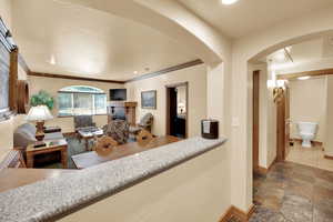 Interior space with stone finish flooring, a fireplace, baseboards, arched walkways, and ornamental molding