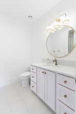 Bathroom with toilet, vanity, baseboards, and tile patterned flooring