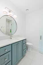 Bathroom featuring walk in shower, baseboards, toilet, tile patterned floors, and vanity