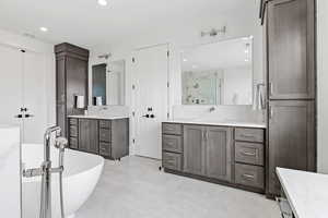 Master bath with recessed lighting, a sink, a stall shower, a freestanding tub, and two vanities
