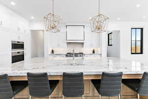 Kitchen featuring an inviting chandelier, white cabinets, and tasteful backsplash