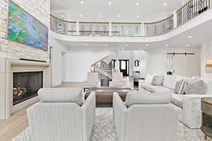 Living area featuring stairs, recessed lighting, a barn door, fireplace, and hardwood floors