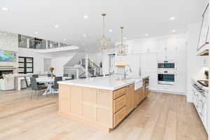 Kitchen with a notable chandelier, farmhouse sink, large island, a fireplace, and open floor plan