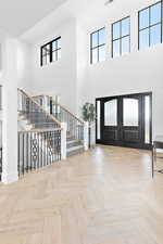 Foyer with a towering ceiling, stairway, and natural light