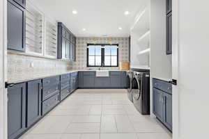 Washroom featuring recessed lighting, a sink, cabinet space, separate washer and dryer, and light tile patterned floors