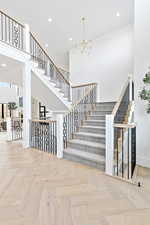 Stairs with baseboards, a towering ceiling, recessed lighting, and an inviting chandelier