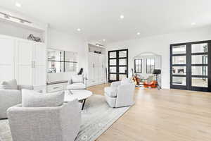 Living room/ music room with french doors, recessed lighting, arched walkways, and hardwood flooring